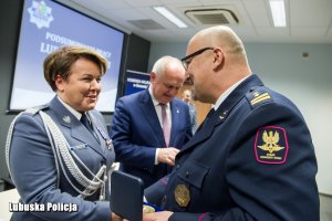 Funkcjonariusz Straży Ochrony Kolei wręcza policjantce okolicznościowy medal.