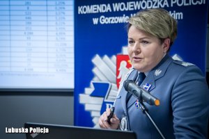 Policjantka przemawiająca z mównicy do mikrofonu.