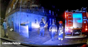 Policjanci i strażak przy wozie strażackim