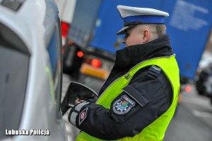 Policjant z dokumentem tożsamości przy kierującym