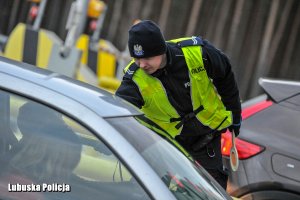 Policjant z urządzeniem do badania trzeźwości przy samochodzie