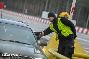 Policjant z urządzeniem do badania trzeźwości przy samochodzie