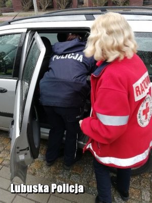 Policjantka usadza dziecko na foteliku. Na bocznym planie ratowniczka medyczna