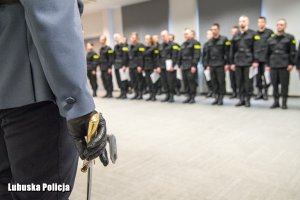 policjant trzymający szablę i nowi policjanci na ślubowaniu