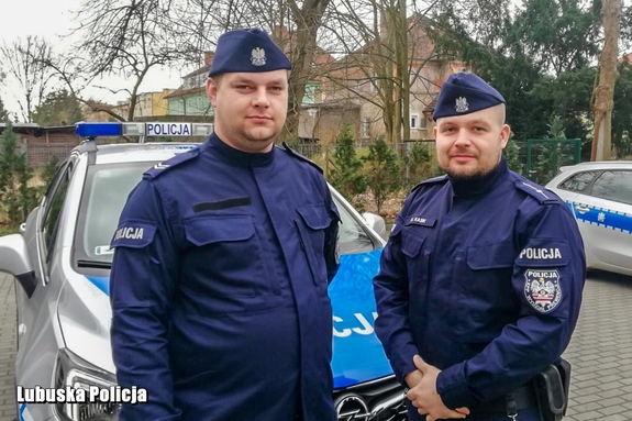 policjanci stoją przed radiowozem