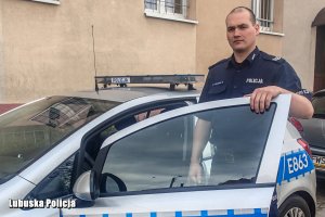 policjant stoi przy radiowozie