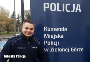 policjant stoi przy banerze zielonogórskiej komendy