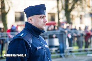 Policjant, a w tle licznie zgromadzone osoby.