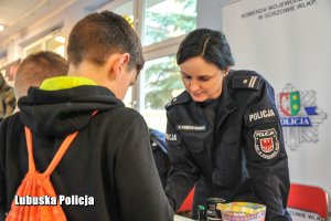 Policjantka przy chłopcu na stoisku profilaktycznym.