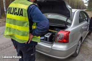 Policjant stoi przy samochodzie.