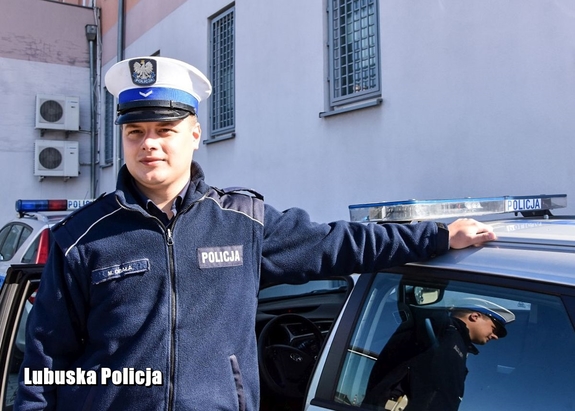 Policjant stoi przy radiowozie