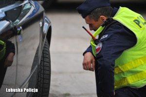 Policjant sprawdza stan ogumienia w pojeździe.