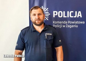 Policjant przy banerze.