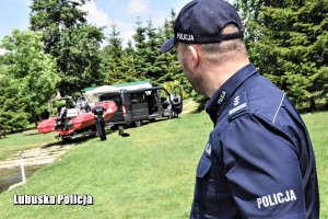 Policjant, a w tle policyjna motorówka.