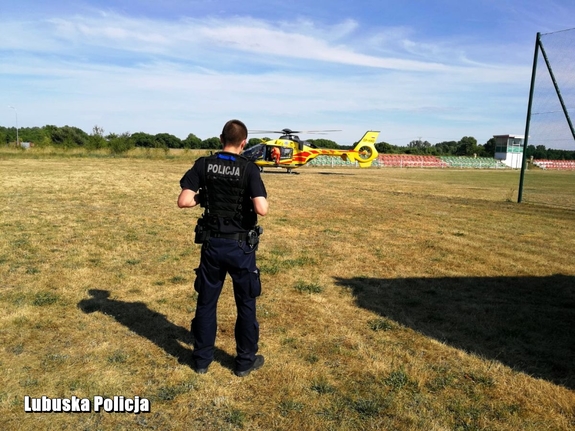 Policjant na tle śmigłowca z Lotniczego Pogotowia Ratunkowego