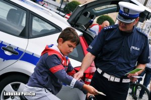 Policjant nakłada element odblaskowy dziecku na rowerze.