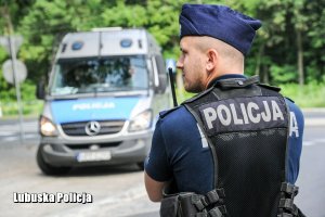 Policjant, a w tle policyjny radiowóz.