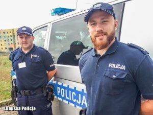 Policjanci stojący przy radiowozie.