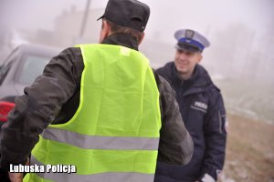 Policjant drogówki przy innej osobie na poboczu drogi.