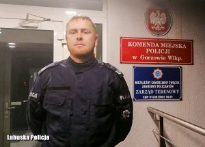 Policjant przed drzwiami wejściowymi do komendy Policji.