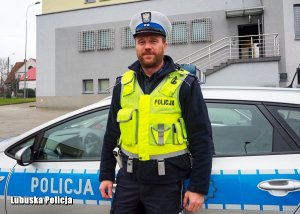 Policjant stojący przy radiowozie.