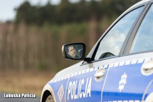 policjant spogląda w boczne lusterko radiowozu