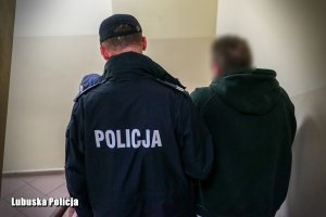 Policjanci prowadza zatrzymanego do celi