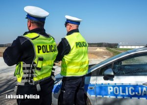 Policjanci ruchu drogowego przed radiowozem