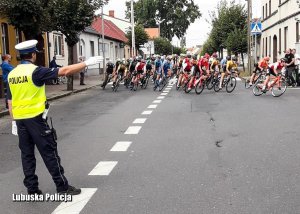 Policjant kieruje ruchem podczas kolarskiego wyścigu.