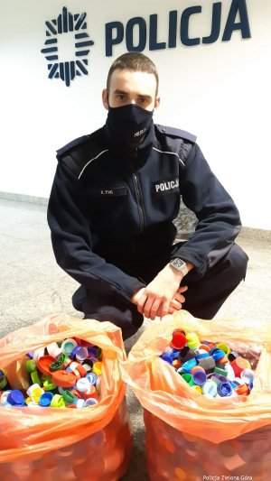 Policjant z Komendy Miejskiej Policji w Zielonej Górze z torbami pełnymi nakrętek