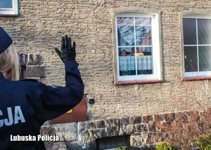 Policjantka machająca do znajdujących się w mieszkaniu dzieci, na które była organizowana zbiórka