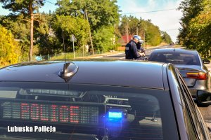 Policjanci kontrolujący kierującego. Na pierwszym planie radiowóz nieoznakowany