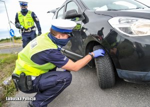 Policjant sprawdza oponę auta.