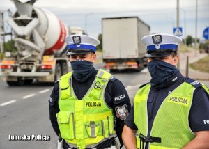 Policjanci drogówki podczas kontroli drogowej przy drodze.