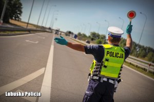 Policjant ruchu drogowego dający znak tarczą do zatrzymania