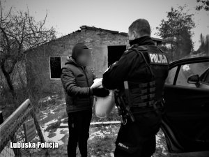 Policjant przekazuje rzeczy osobie bezdomnej