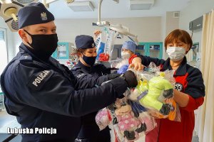 policjant i policjantka przekazują zabawki pracownikom szpitala
