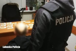policjant obserwuje podejrzanego siedzącego przed biurkiem, na którym leżą pieniądze