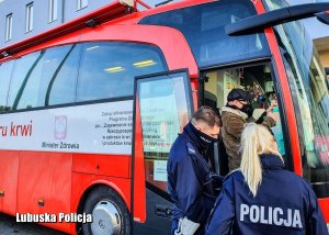 Krwiobus zaparkowany przed nowosolską komendą, w wejściu stoją policjanci.