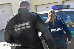 Policjantka i strażnik graniczny na tle radiowozu.