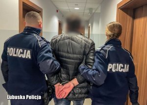 Policjanci przeprowadzają zatrzymanego do sprawy mężczyznę