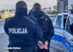 Policjanci przeprowadzają zatrzymanego do sprawy mężczyznę