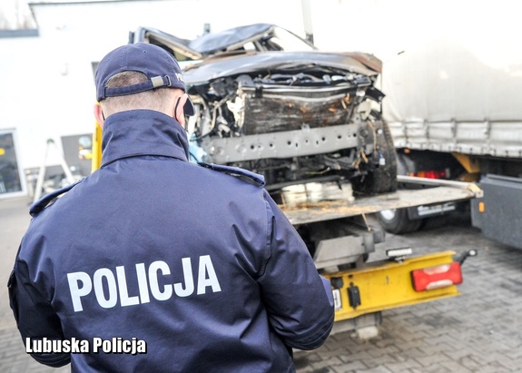 Policjant przy lawecie przeprowadza oględziny zabezpieczonego pojazdu