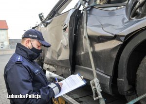 Policjant przy lawecie przeprowadza oględziny zabezpieczonego pojazdu