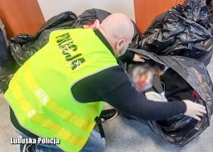 Policjant dokonujący oględzin zabezpieczonej, podrabianej odzieży