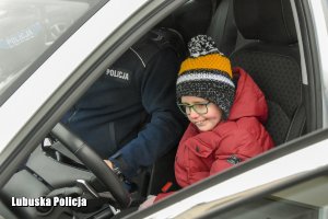 Policjant z chłopcem we wnętrzu policyjnego radiowozu.