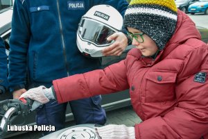 Chłopczyk siedzący na policyjnym motocyklu, obok stojący policjant.