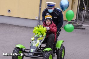 Policjant pcha pojazd, w którym siedzi chłopiec.