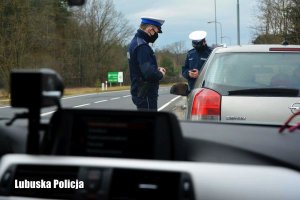 Widok z radiowozu na policjantów kontrolujących kierowcę