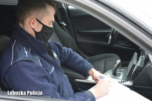 Policjant w radiowozie spisujący dokumentację